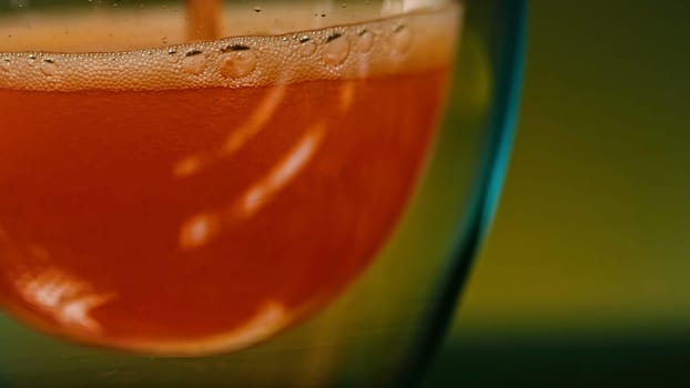 Close up of pouring whiskey into a glass on a colorful blurred wall background. Stock clip. Alcoholic drink inside glass