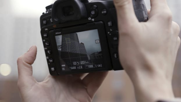 Discover new places,close up of taking pictures of a new high rise building. Female hands with a professional camera taking pictures at urban modern architecture.