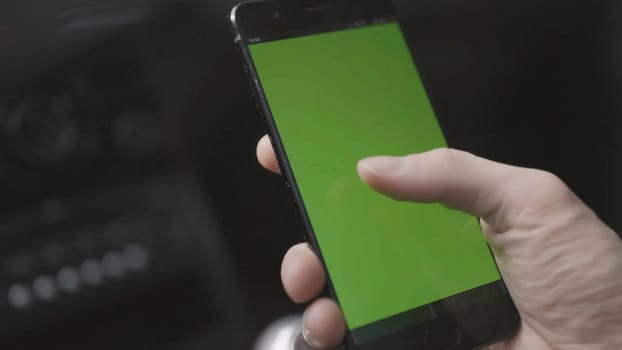 Close-up of man tapping on green phone screen. Stock. Man tapped green screen of phone to view map and removed it. Man looks at green screen of phone as if it's map.