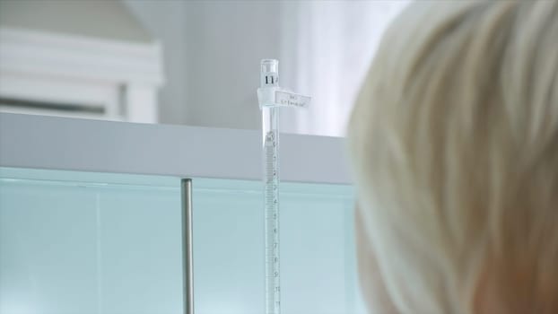 Woman conducts laboratory experiments and analyzes. Clip. Woman looks at chemical liquid in laboratory. Industrial laboratory with workers and chemicals in test tubes.