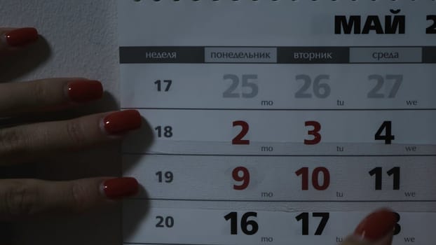 Woman moving date on calendar. Concept. Woman moves calendar slider. Woman marks new day of week on calendar.