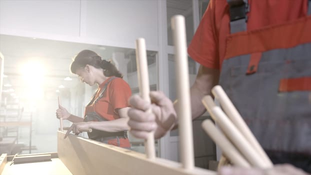 Wooden furniture mounts. Action. Close-up workers put wooden dowels in frame. Connection of wooden furniture details. Fixing furniture with round wooden sticks.