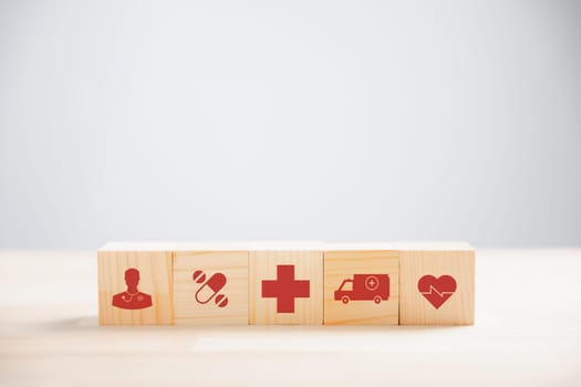 Wooden cube blocks form a pyramid stack topped with a medical icon, illustrating healthcare and insurance concepts. white background with copy space for health, medical technology, vaccination ideas.