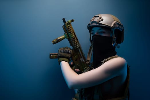 sexy girl soldier in a helmet, armed with an automatic rifle, in military clothes on a blue background