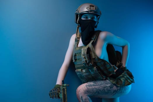 sexy girl soldier in a helmet, armed with an automatic rifle, in military clothes on a blue background
