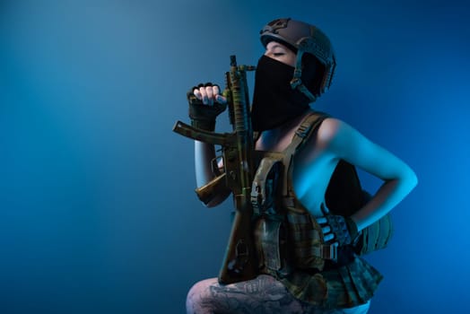 sexy girl soldier in a helmet, armed with an automatic rifle, in military clothes on a blue background