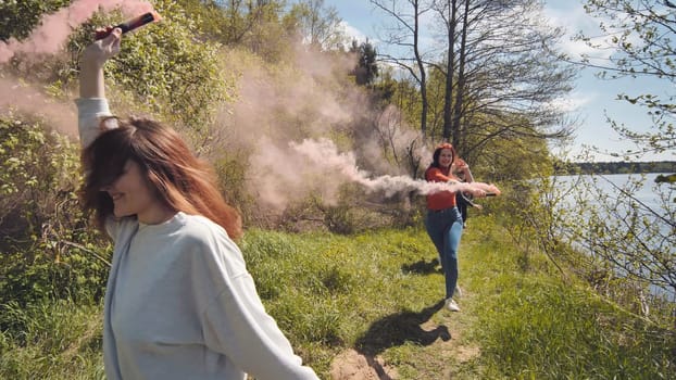 School children run with coloured smoke by the woods