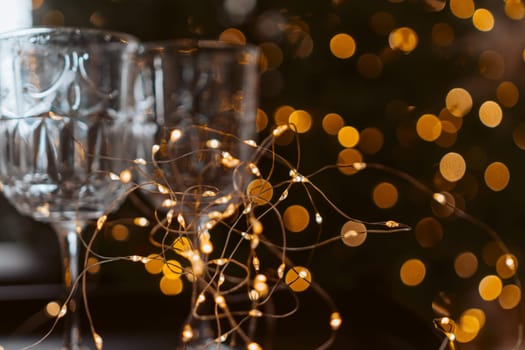 Champagne glasses, New Year decor. New Year's festive setting, family holidays.Two glasses of champagne are on the table against the background of New Year's decorated tree