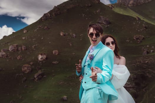 wedding couple hugs and looks at the camera, cheerful groom jokes. photography in the mountains in summer, close-up.