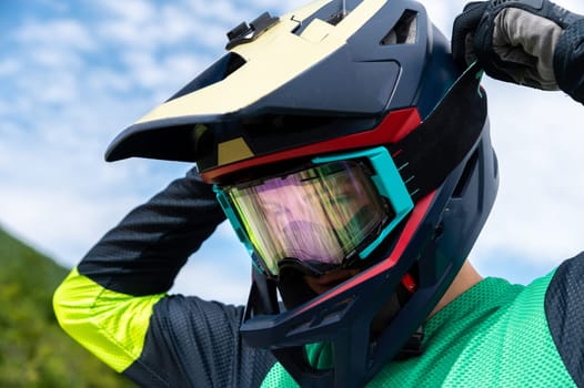 Guy adjusting motorcycle motocross helmet with goggles, close-up shot of relaxing while riding bike or dirt bike.