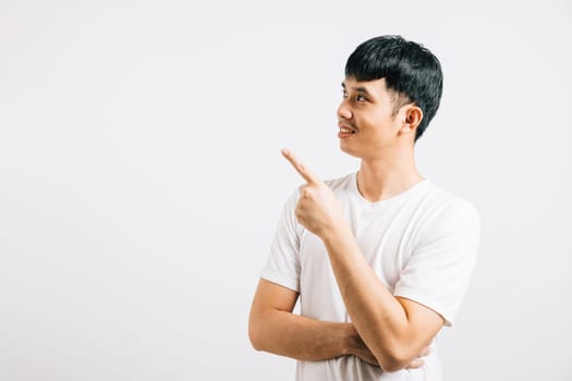 An Asian man with a friendly smile points his finger with confidence, directing attention to empty space. Studio shot isolated on white, highlighting his positive and professional demeanor.