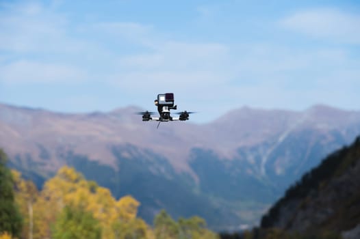 A drone with an action camera films mountains in flight. close-up of an unmanned device, fpv with camera.