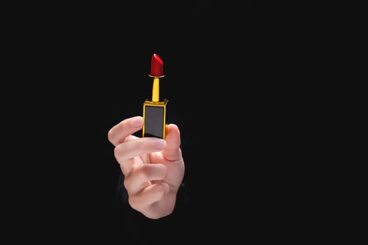 Red lipstick in a woman's hand on a dark background. Girl holding a popular cosmetic product.