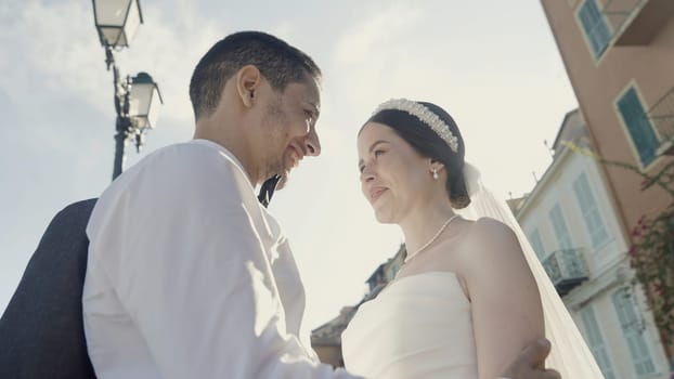 A wedding party with happy faces. Action. The newlyweds on whom the rose petals are thrown pose and smile brightly next to the registry office. High quality 4k footage