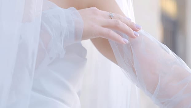 Close-up of bride with veil and white outfit. Action. Beautiful delicate details of bride's outfit. White veil on young bride.