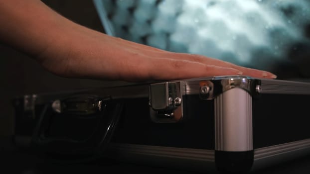Close up of female hand opening metal briefcase. Woman opening the aluminum carrying case and lifting its lid, concept of mystery.