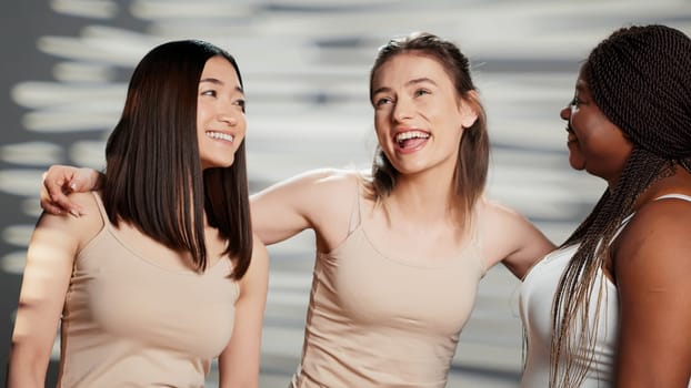 Interracial group of girls smiling for body acceptance campaign, laughing together and promoting body positivity. Beauty models with glowing skin and different body types showing femininity.