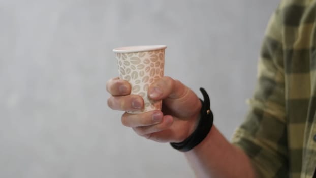 Man holding white cup then it changed to paper cup for coffee. A man is holding a brown paper cup. Man holding blank cup, close up.