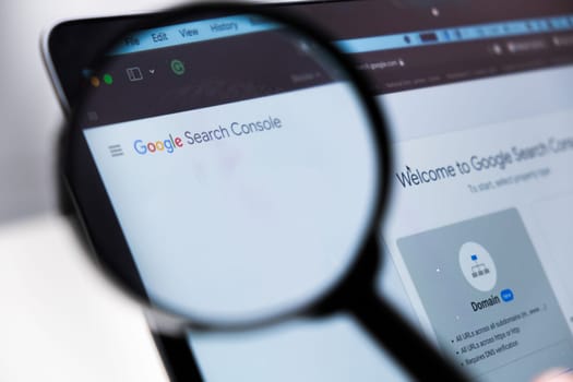 Google Search Console logo enlarged through a magnifying glass on a laptop screen, December 2023, Prague, Czech Republic