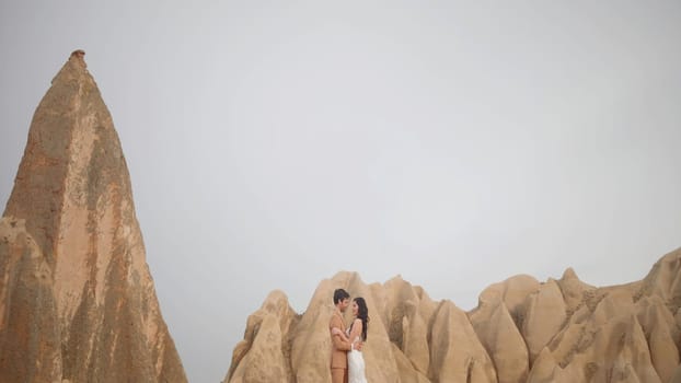 Beautiful young couple on the background of tops of mountains in Cappadocia, Turkey. Action. Action. Romantic love of man and woman couple in Cappadocia