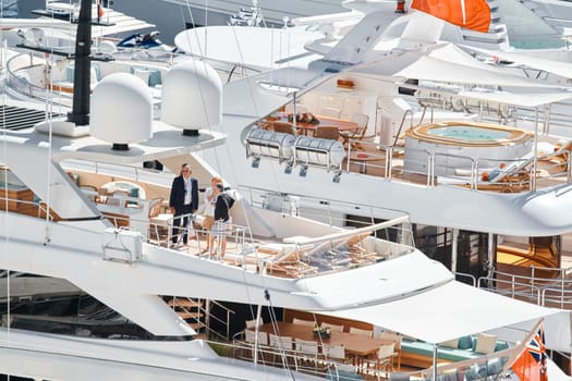 Monaco, Monte Carlo, 27 September 2022 - Invited wealthy clients inspect megayachts at the largest fair exhibition in the world yacht show MYS, port Hercules, yacht brokers, sunny weather. High quality photo