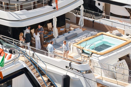 Monaco, Monte Carlo, 27 September 2022 - Invited wealthy clients inspect megayachts at the largest fair exhibition in the world yacht show MYS, port Hercules, yacht brokers, sunny weather. High quality photo