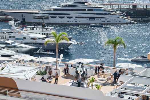 Monaco, Monte Carlo, 27 September 2022 - Rich clients visitors examine a helicopter standing on the deck of a yacht club, the largest fair yacht show, port Hercules, yacht brokers, sunny weather. High quality photo