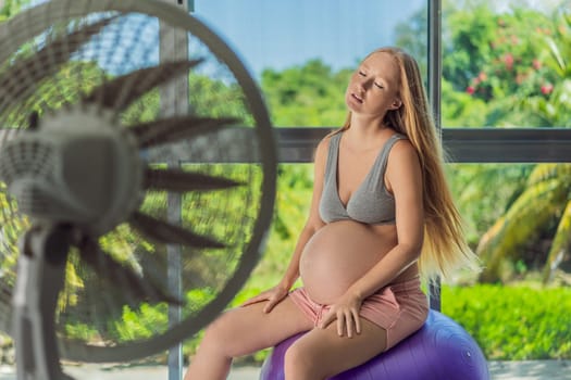 A pregnant woman seeks relief from an abnormal heatwave by using a fan, ensuring her comfort and well-being during sweltering conditions.