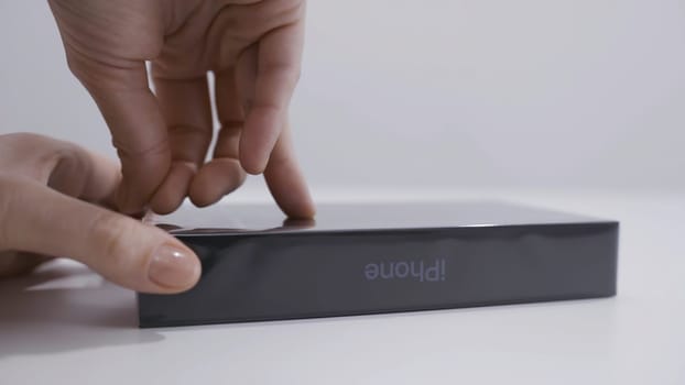 MOSCOW, RUSSIA-NOVEMBER, 2020: Close-up unboxing of iPhone. Action. Close-up of man opening box from new iPhone. Man's hand peels off film from box with new smartphone.