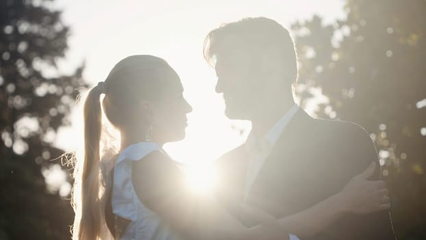 Posing of the newlyweds. Action.A beautiful young couple with a blonde girl in big earrings and her husband with a beard who are sitting and hugging on the street and the bright rays of the sun are shining. High quality 4k footage