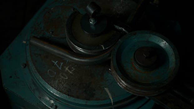 A worker works on a pipe bending machine at a steel plant. Creative. Industrial machine at industrial factory