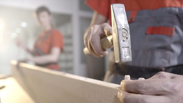 Wooden furniture mounts. Action. Close-up workers put wooden dowels in frame. Connection of wooden furniture details. Fixing furniture with round wooden sticks.
