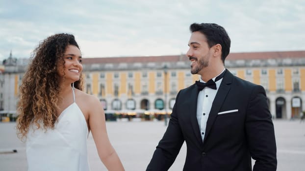 Young couple walking around the city on their wedding day. Action. Bride and groom holding hands during walking in city