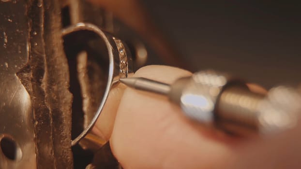 The jeweller is setting a precious stone. Craft jewelery making. Ring repairing. Putting the diamond on the ring. Macro video. Craft jewelery making with professional tools. Putting the diamond on the ring. Macro photo.
