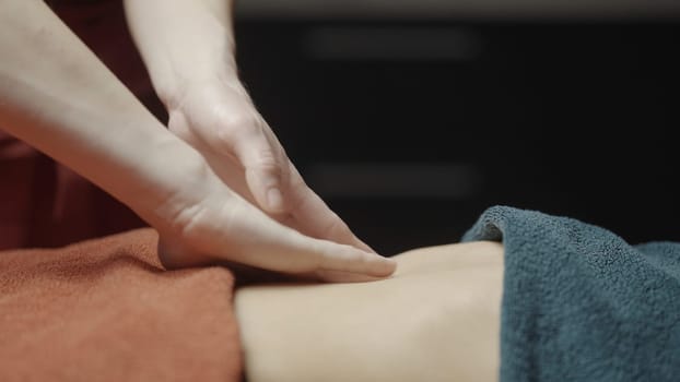 Close-up of masseur smoothly doing massage. Action. Gentle smoothing movements of masseur. Masseur does relaxing massage. Spa salon.