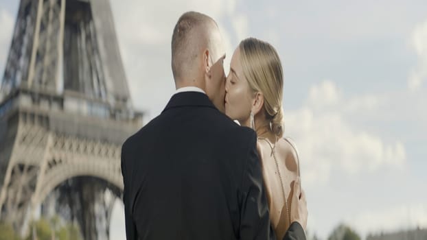 A kissing European couple. Action. A young beautiful blonde woman with her man kissing on the background of the Eiffel Tower. High quality 4k footage