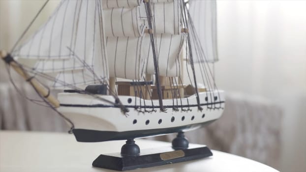 Wooden ship toy model standing on a wooden table in light room, hobby concept. Close up of the sailing ship small figure.