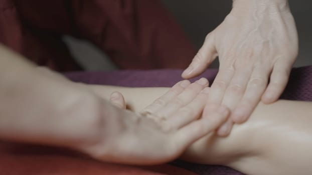 Close-up of masseur smoothly doing massage. Action. Gentle smoothing movements of masseur. Masseur does relaxing massage. Spa salon.