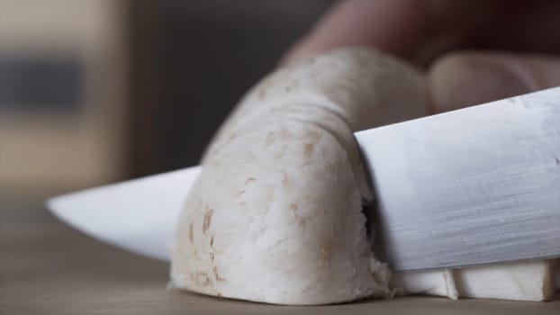 Pieces of champignons, close up of hands cutting the mushrooms into even pieces with a knife, cooking food, vegan, dietary concept. Blade of knife cutting champignons in the kitchen.