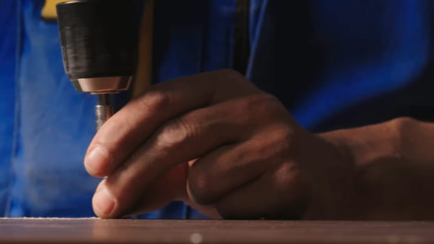 Close-up of worker drilling nails with drill. Creative. Man screws nails with drill. Drilling with drill during crafting work.
