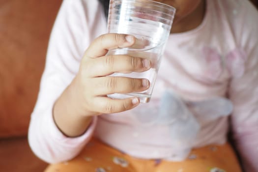 child hand holding a glass of water .