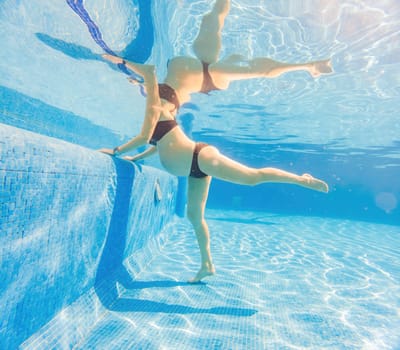 Embracing aquatic fitness, a pregnant woman demonstrates strength and serenity in underwater aerobics, creating a serene and empowering image in the pool.