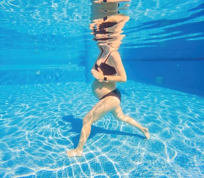 Embracing aquatic fitness, a pregnant woman demonstrates strength and serenity in underwater aerobics, creating a serene and empowering image in the pool.