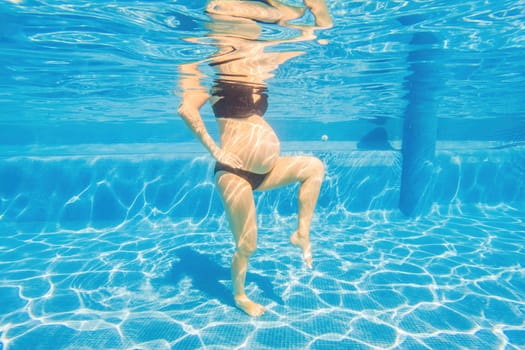 Embracing aquatic fitness, a pregnant woman demonstrates strength and serenity in underwater aerobics, creating a serene and empowering image in the pool.