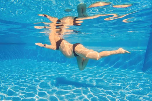 Pregnant serenity submerged a woman gracefully dives into the pool, celebrating the beauty of pregnancy with aquatic elegance.