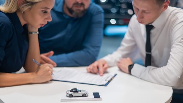 Happy caucasian couple signs a contract for the purchase of a car salon