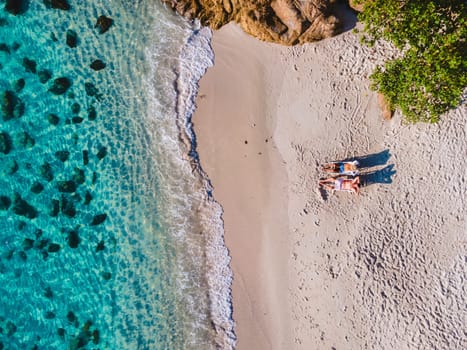 Koh Samet Island Thailand, aerial drone view from above at a couple of men and woman on the beach of Samed Island in Thailand with a turqouse colored ocean and a white tropical beach from above