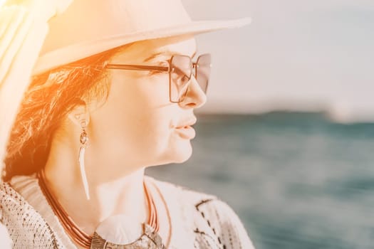 Portrait of a curly haired woman in a white hat and glasses on the background of the sea