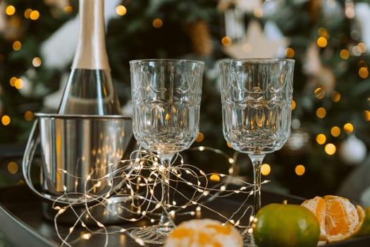 Champagne glasses, New Year decor. New Year's festive setting, family holidays.Two glasses of champagne are on the table against the background of New Year's decorated tree