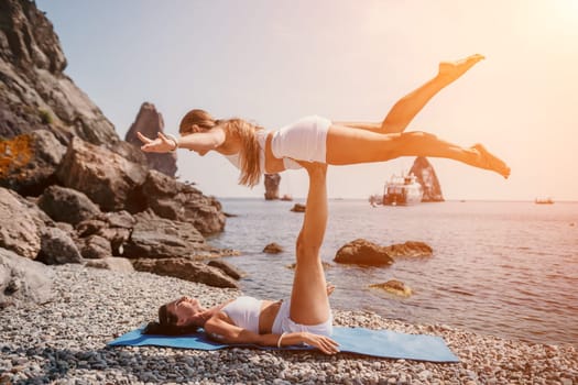 Woman sea yoga. Back view of free calm happy satisfied woman with long hair standing on top rock with yoga position against of sky by the sea. Healthy lifestyle outdoors in nature, fitness concept.